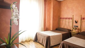 Une chambre avec deux lits simples, une table de chevet avec une lampe et une plante en pot.