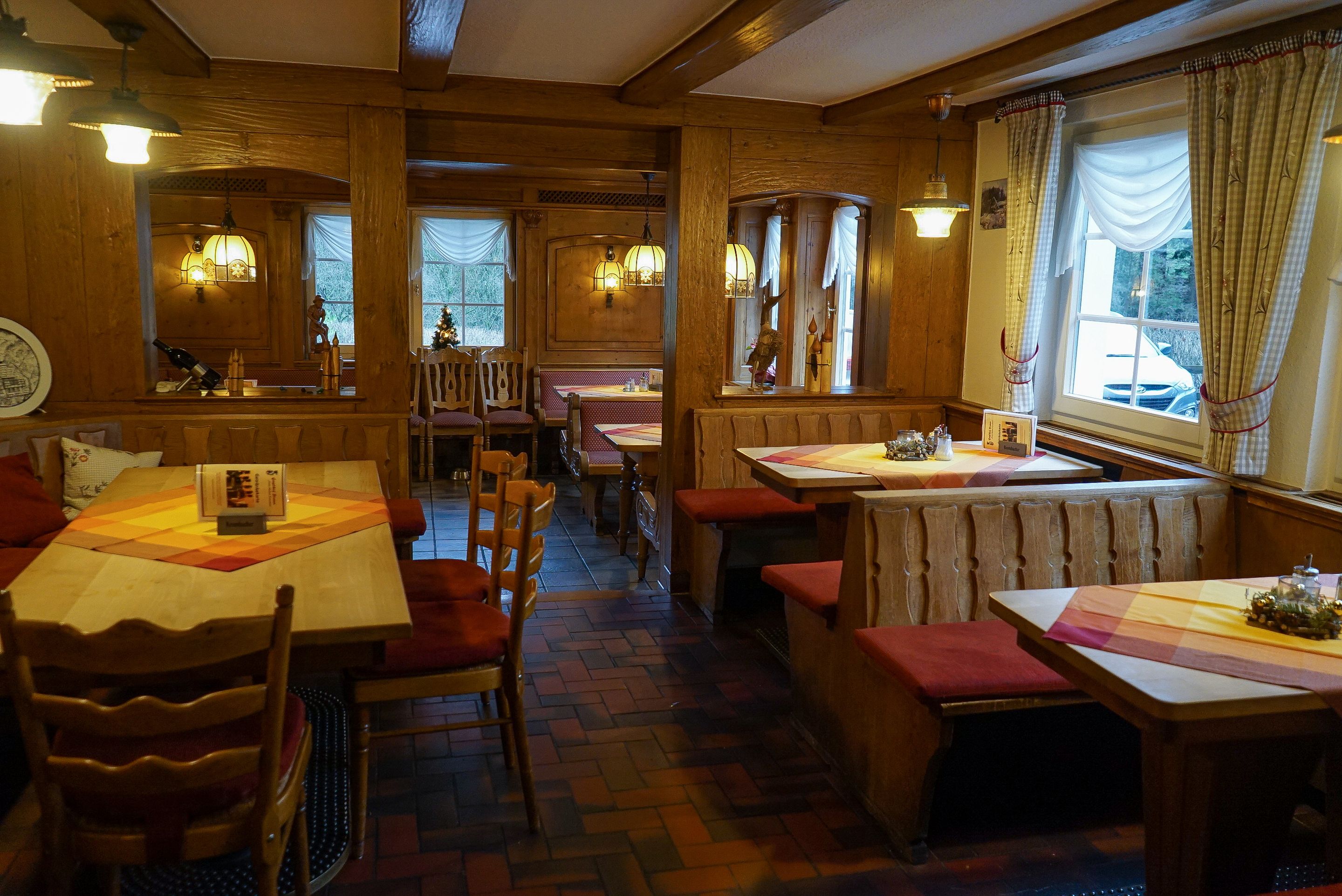 A cozy restaurant with wooden interiors, multiple tables and booths, and warm lighting.