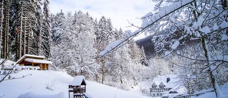 A snow-covered cabin with a wooden deck and a small play structure.