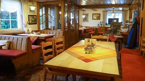 Un restaurante acogedor con muebles de madera, una mesa larga con un mantel individual y una chimenea.