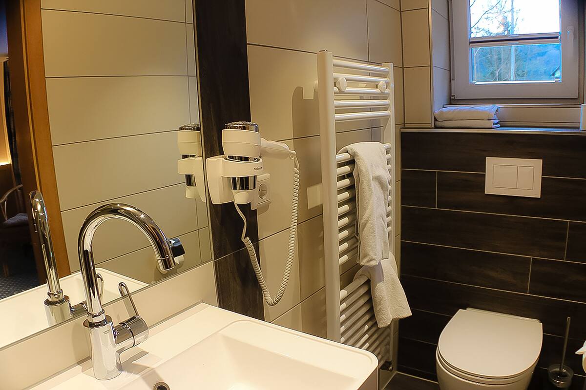 Une salle de bain moderne avec un lavabo blanc, un robinet chromé et un porte-serviettes sur lequel est posée une serviette blanche.