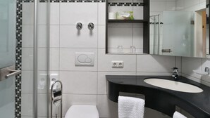 A modern bathroom with a glass-enclosed shower, a white toilet, a black sink with a mirror above it, and a towel rack. - Landhaus Marga (Fischen im Allgaeu)