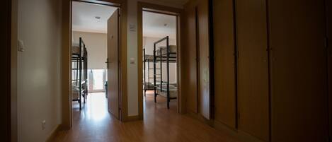 A hallway with wooden flooring leading to a room with bunk beds.