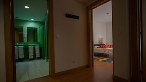 Una habitación de hotel con piso de madera, una cama con almohada a rayas rojas y blancas y una alfombra de colores con rayas.
