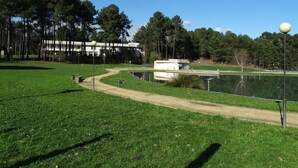 Un parque con un estanque, un sendero y un edificio al fondo.
