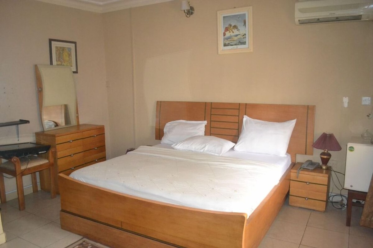 A bedroom with a wooden bed, a dresser, a desk, and a nightstand.