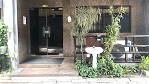 Zona d'entrada amb taulell de recepció, porta de vidre i un petit rentapeus.