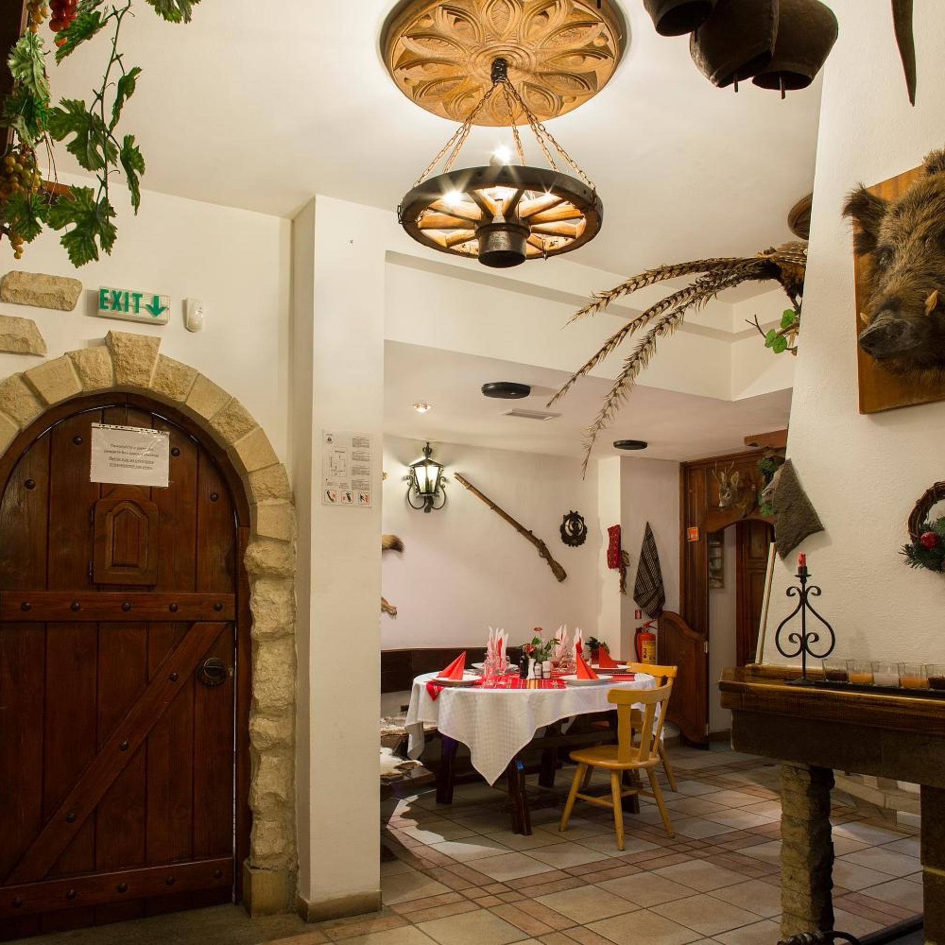A rustic interior with a stone archway, a wooden table set for dining, and a decorative ceiling light.