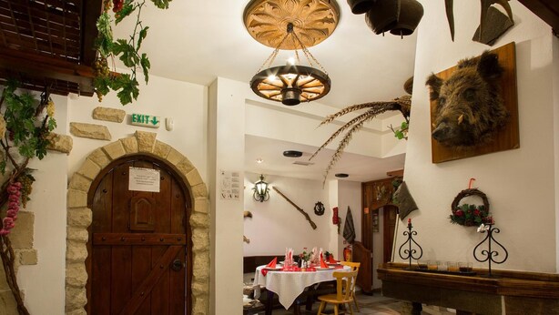 Un interior rústico con puerta de madera, arco de piedra y comedor con mesa dispuesta para dos.