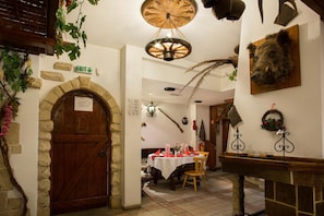 Un interior rústico con puerta de madera, arco de piedra y comedor con mesa dispuesta para dos.