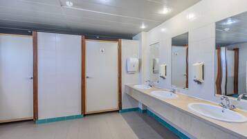 Des toilettes publiques équipées de trois lavabos, de miroirs et de sèche-mains.