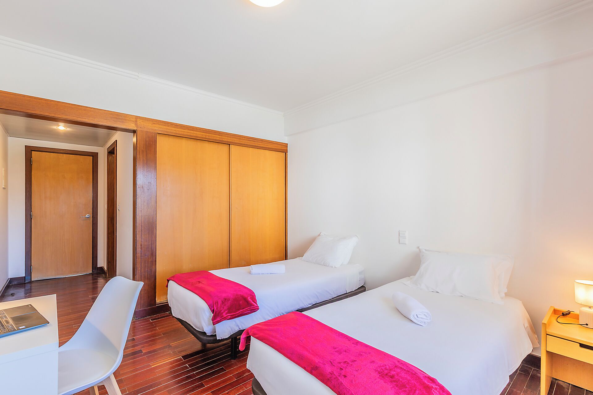Une chambre d’hôtel avec deux lits, un bureau et une chaise.