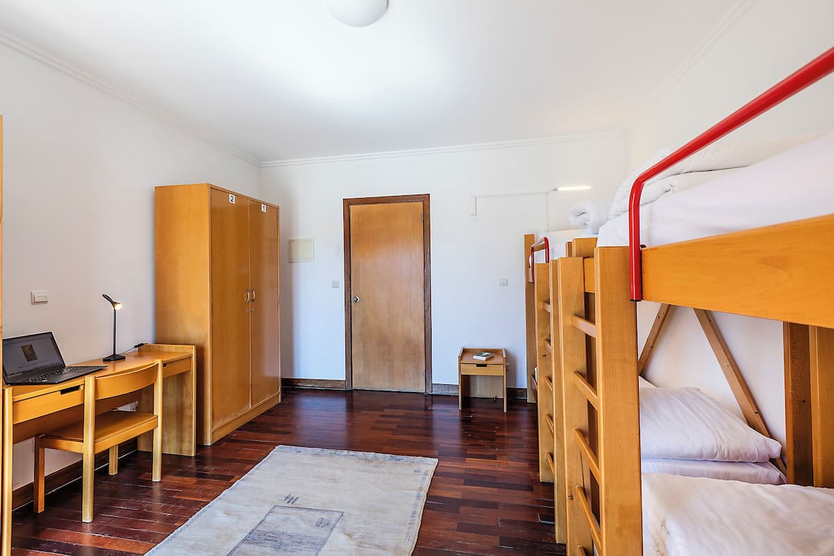 Une chambre de dortoir équipée de lits superposés, d’un bureau, d’une chaise, d’un ordinateur portable et d’une armoire.