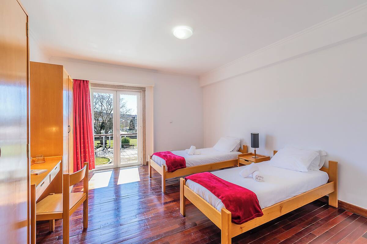 Une chambre d’hôtel avec deux lits en bois, un bureau et une chaise.