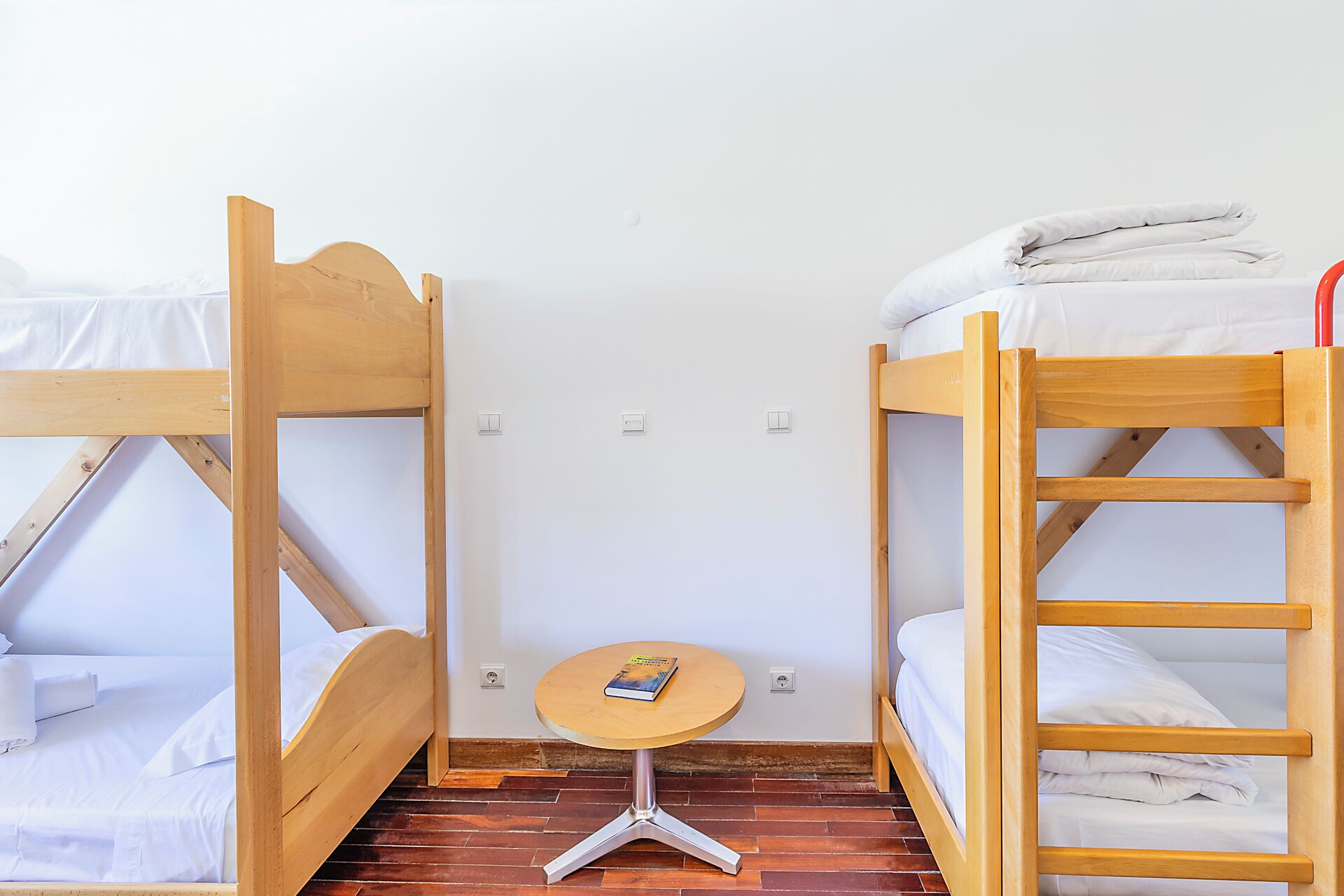 Een slaapkamer met een stapelbed, een klein rond tafeltje en een boek.