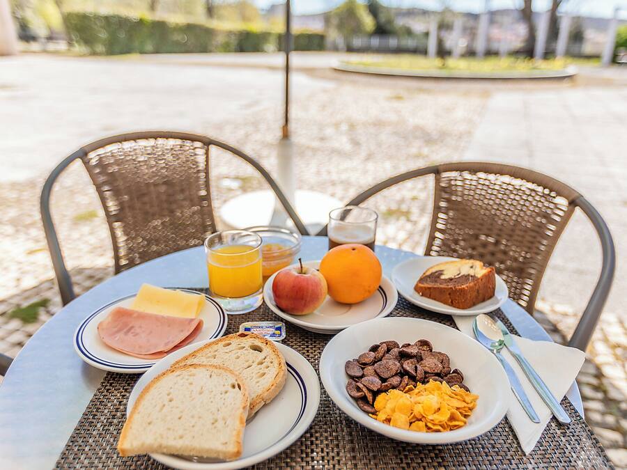 A breakfast table with plates of food, a glass of orange juice, and a bowl of cereal.
