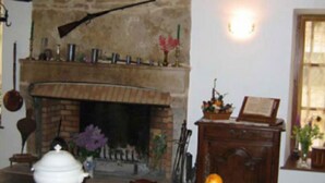 A room with a fireplace, a wooden cabinet, and a fruit basket on a table. - La Ferme du Coucou (Prenois)