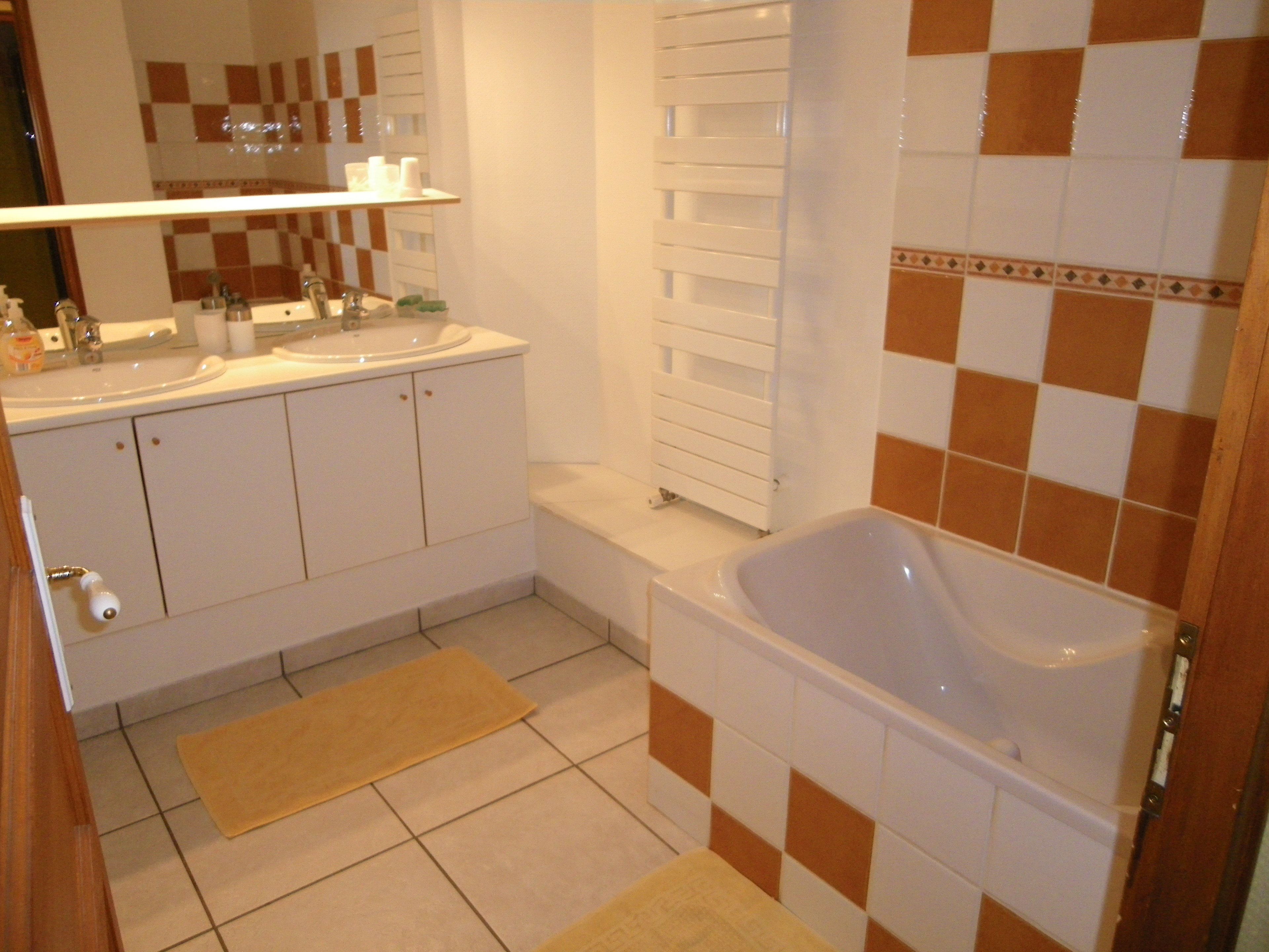 A bathroom with a bathtub, two sinks, a mirror, and a towel rack.