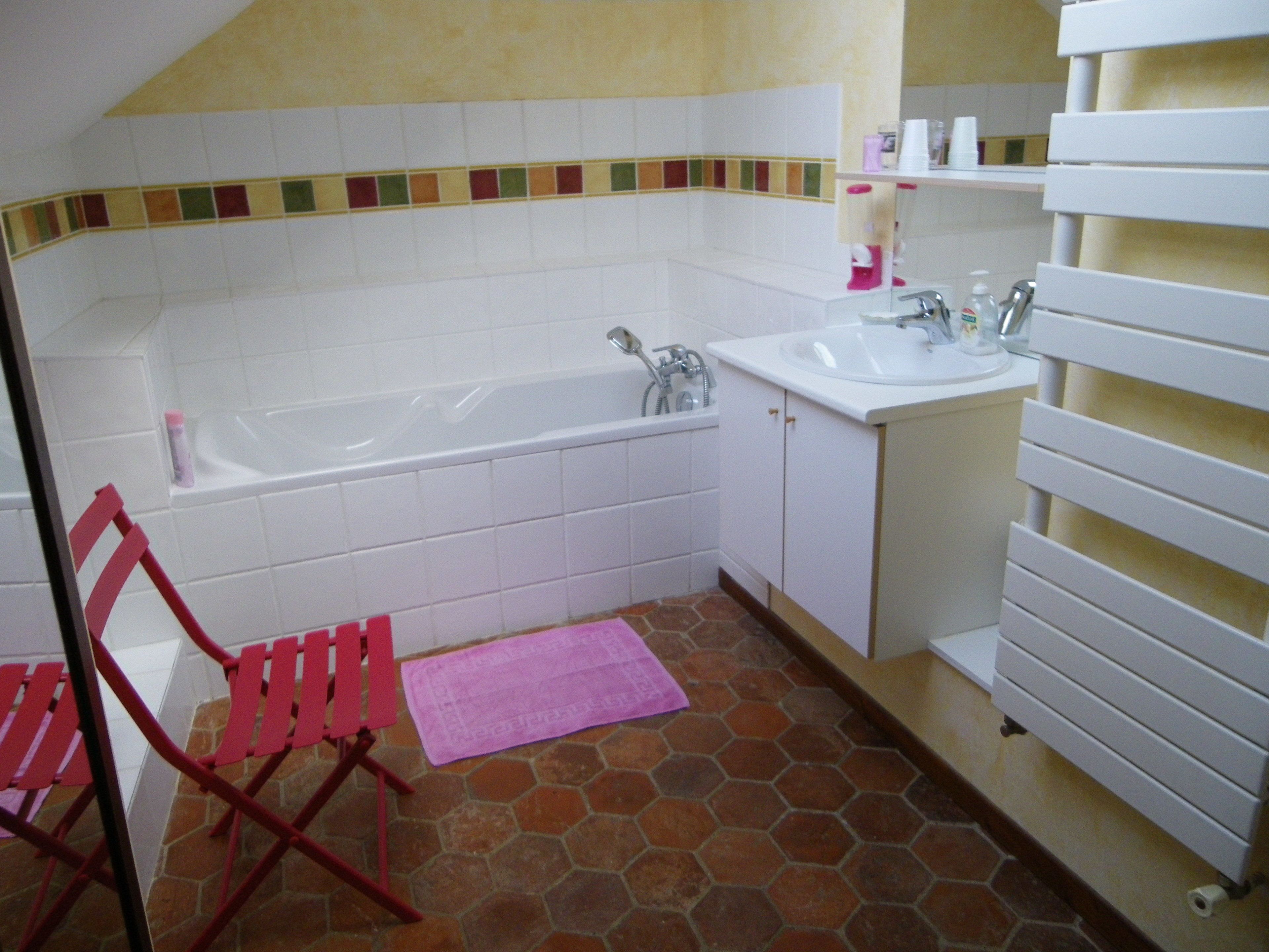 A bathroom with a bathtub, sink, and tiled floor.