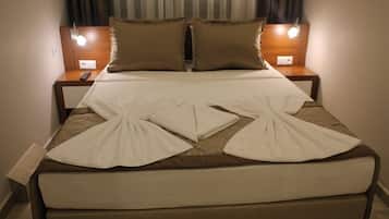 A neatly made bed with a white duvet and two pillows, a bedside table with a lamp, and a window with curtains.