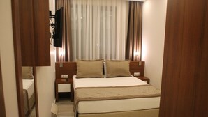 A hotel room with a bed, bedside tables, a TV, and curtains. - Erzincan Mesut Hotel (Erzincan)