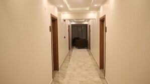 A hotel hallway with a marble floor, wooden doors, and a seating area at the end. - Erzincan Mesut Hotel (Erzincan)