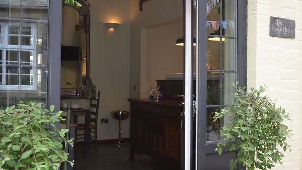 A cozy interior with a wooden counter, a mirror, and a dining area visible through an open door. - Rosemount Boutique B&B (Lanark)