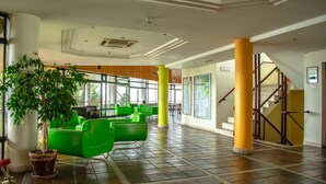 A spacious lobby with green seating, a large plant, and a staircase.