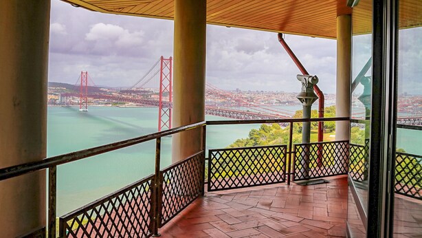 A balcony with a view of a bridge and cityscape.