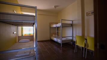 Un dormitorio con literas, una mesita y una silla.