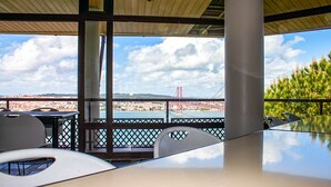 A modern outdoor dining area with a clear view of a bridge and cityscape.