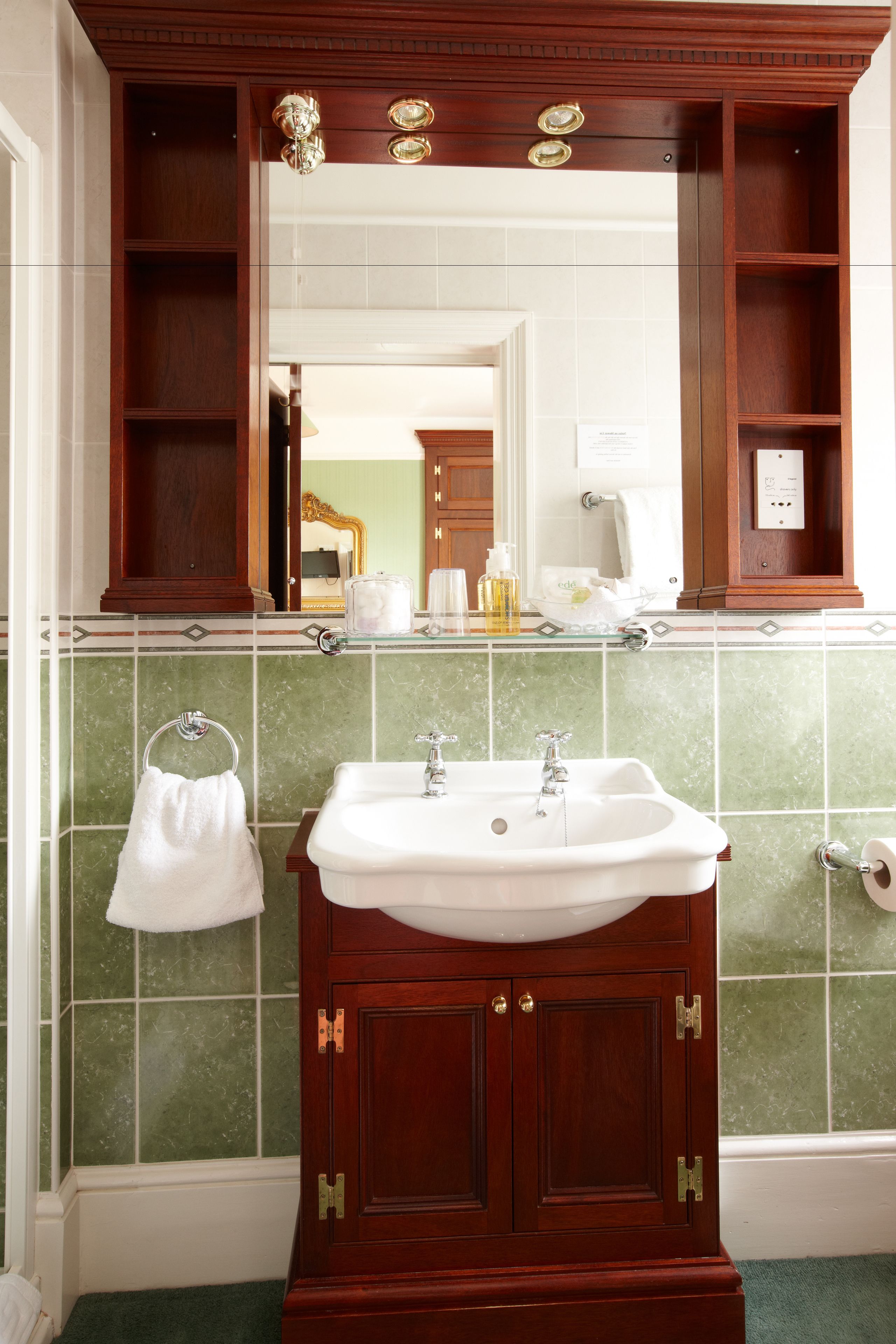 A bathroom with a wooden vanity, a white sink, and a mirror above it.