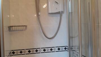 A shower with a handheld showerhead, a control panel, and a glass door.