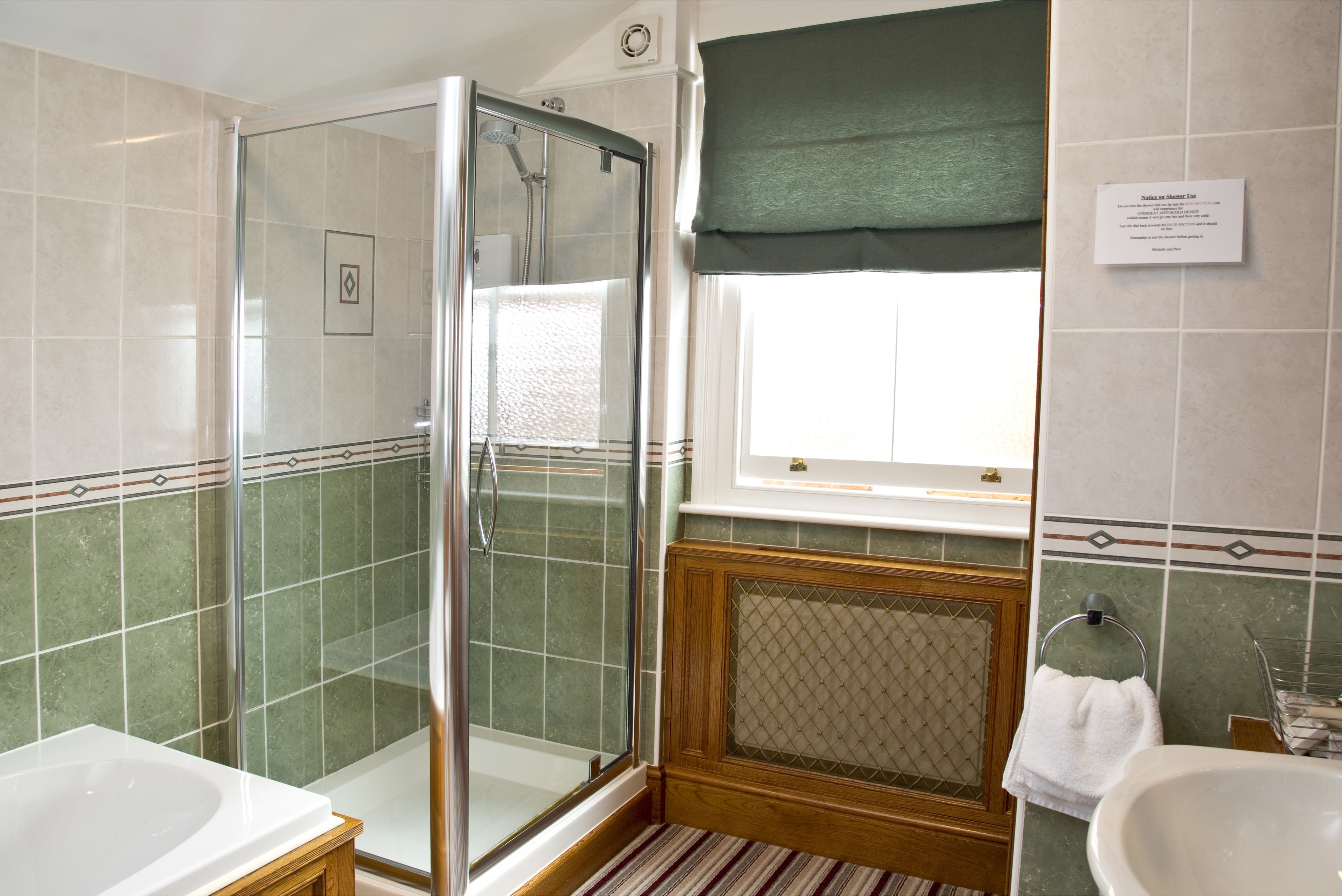 Un bagno con doccia vetrata, una vasca da bagno bianca e un lavabo con porta asciugamani.