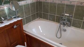 A bathroom with a bathtub, a wooden vanity, a mirror, and a toilet.