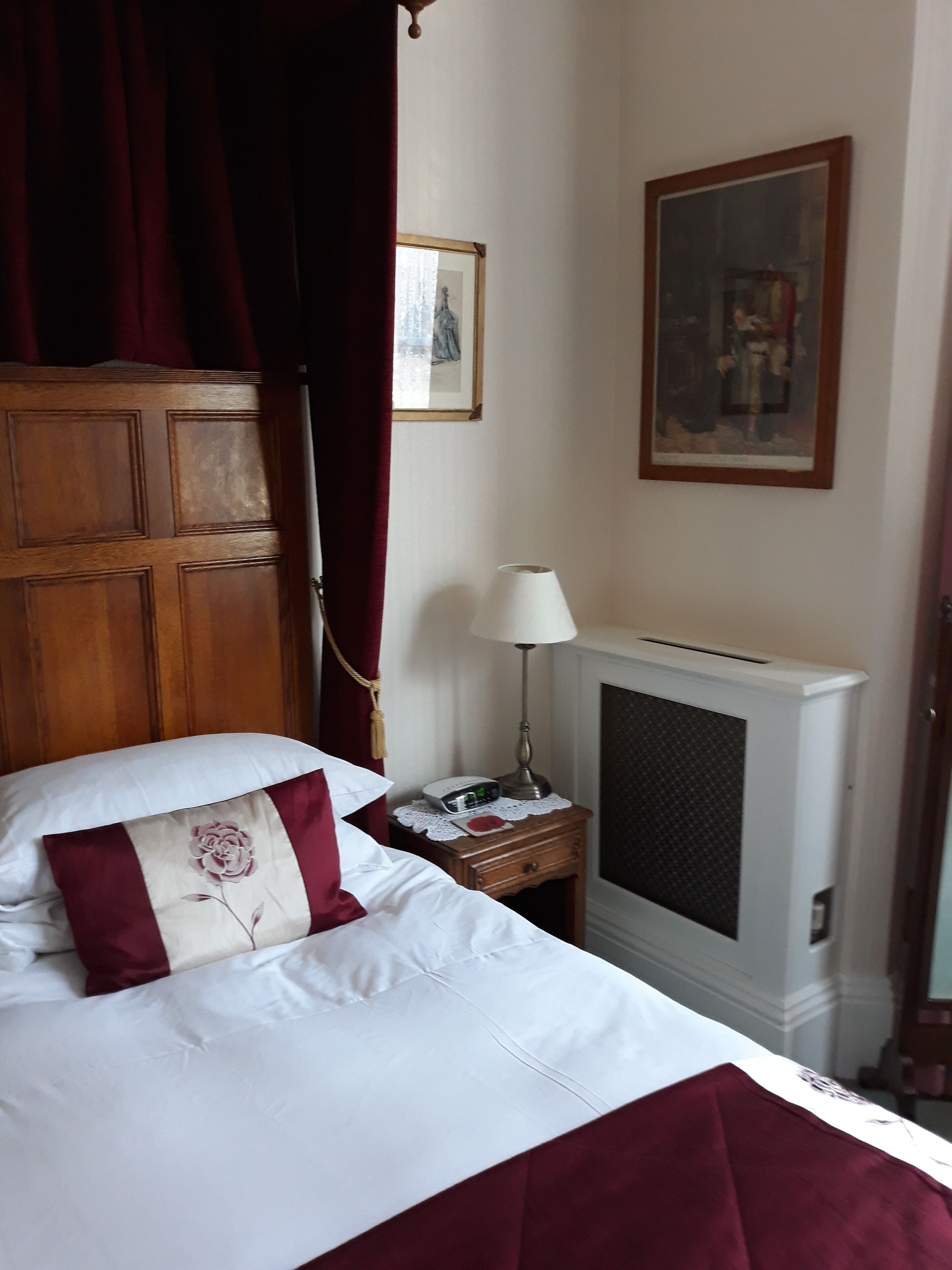 Une chambre d’hôtel avec un lit, une table de chevet avec une lampe, un tableau au mur et une cheminée.