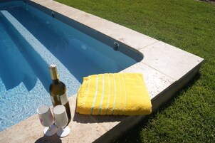 Una piscina con una toalla amarilla y dos copas de vino en el borde.