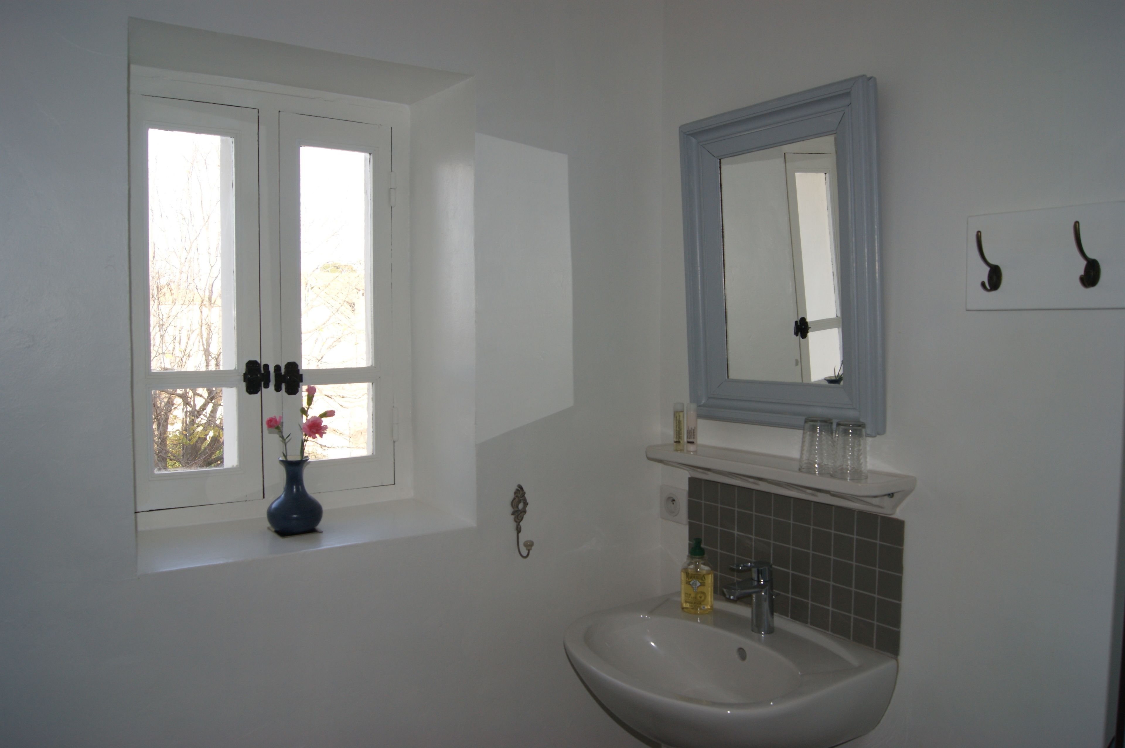 A bathroom with a window, a sink, and a mirror.