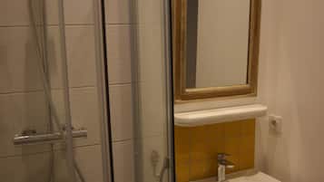 A bathroom with a glass shower enclosure, a white sink, and a mirror above it.