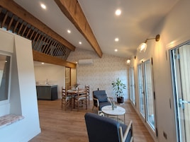Una habitación amplia con techo de madera, un comedor con sillas y mesa, un sofá y una planta en maceta.