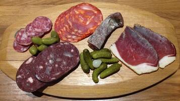 Una tabla de madera con diversos embutidos y aceitunas.