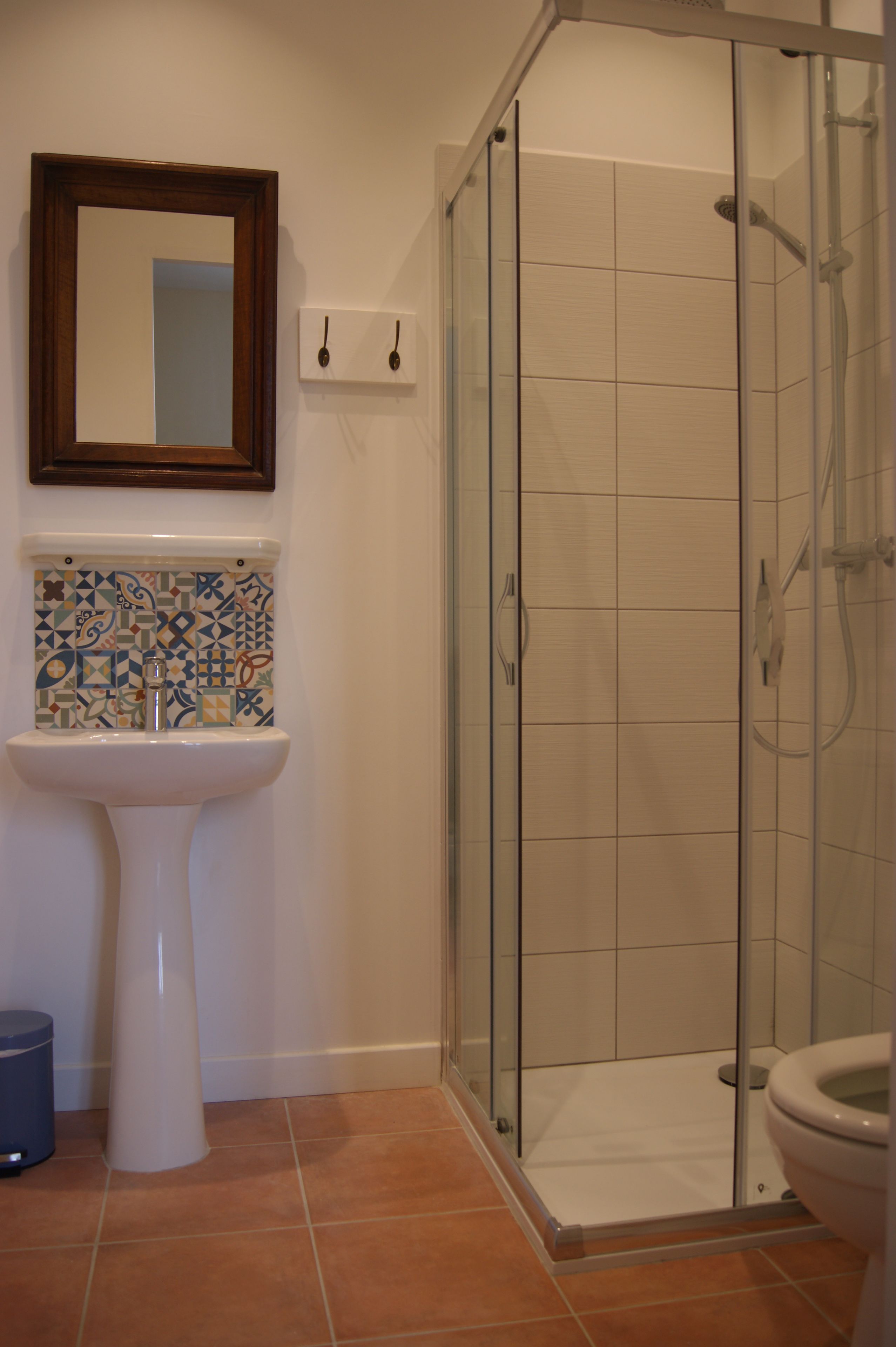 A bathroom with a tiled shower, a sink, and a mirror.