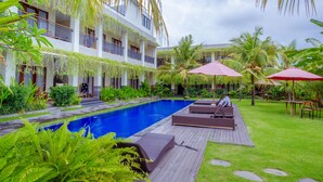 Un hôtel doté d’une piscine, de chaises longues et de palmiers.