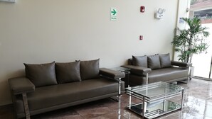 A modern waiting area with two sofas and a glass coffee table. - Hotel Candamo (Lima)