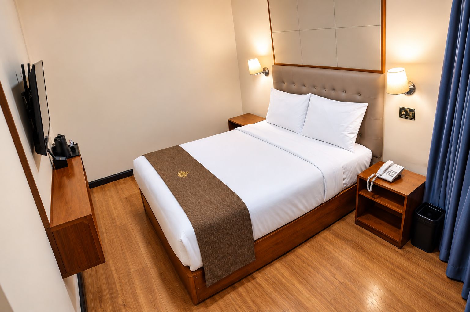 Habitación de hotel con cama, mesitas de noche, televisor, teléfono y cesto de basura.