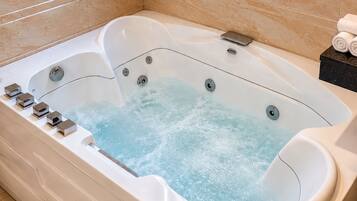 A modern bathroom with a large bathtub, a window, and a tiled floor.