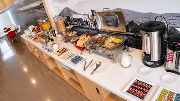 A buffet with various food items, a coffee machine, and a milk jug.