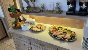 A buffet setup with various food items and a decorative frog figurine. - Pension Nadia (Adorf)