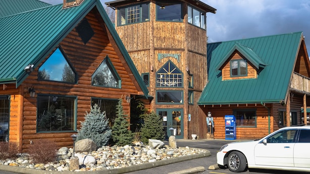 A rustic log cabin-style building with a prominent tower and a sign that reads "Restaurant."