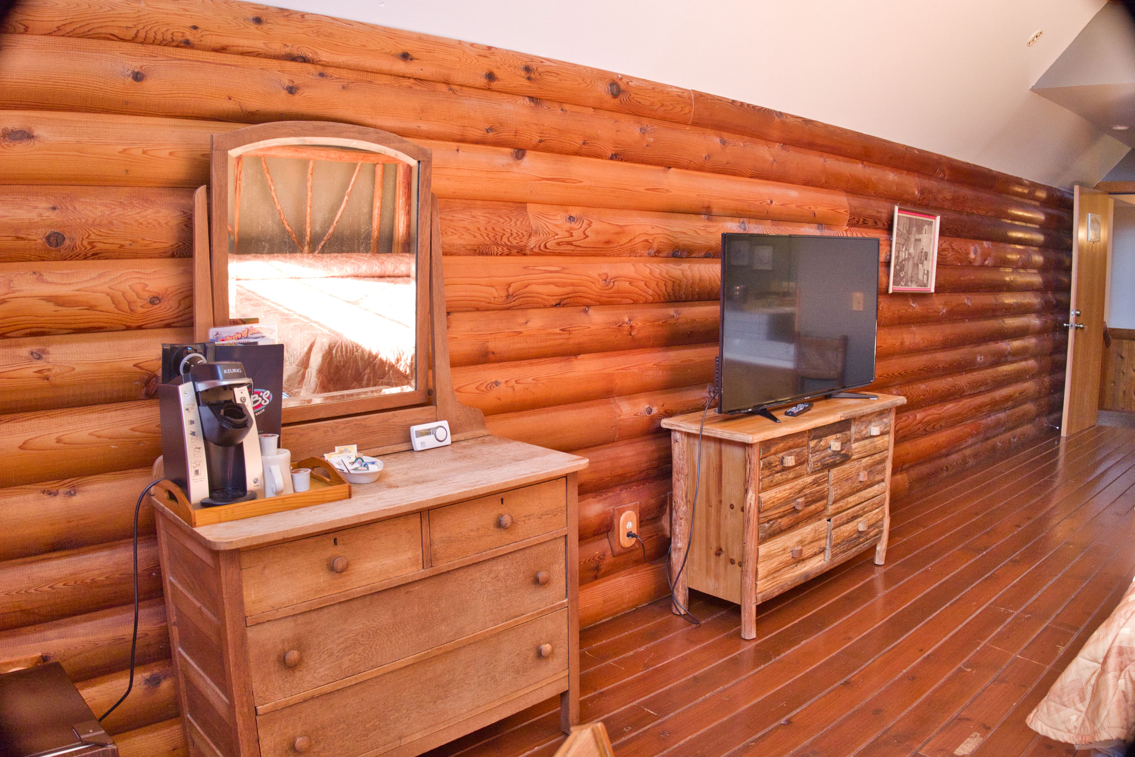 Una habitación tipo cabaña de madera con un aparador, televisor y un espejo grande.